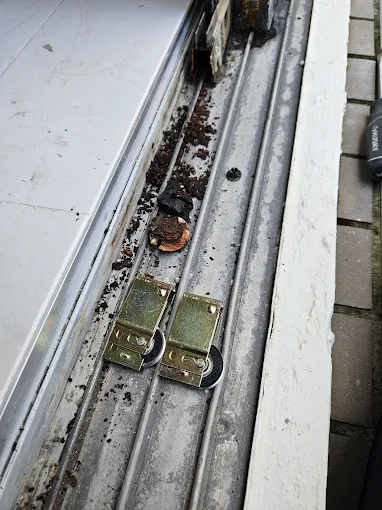 Close-up of a worn sliding door track filled with grime